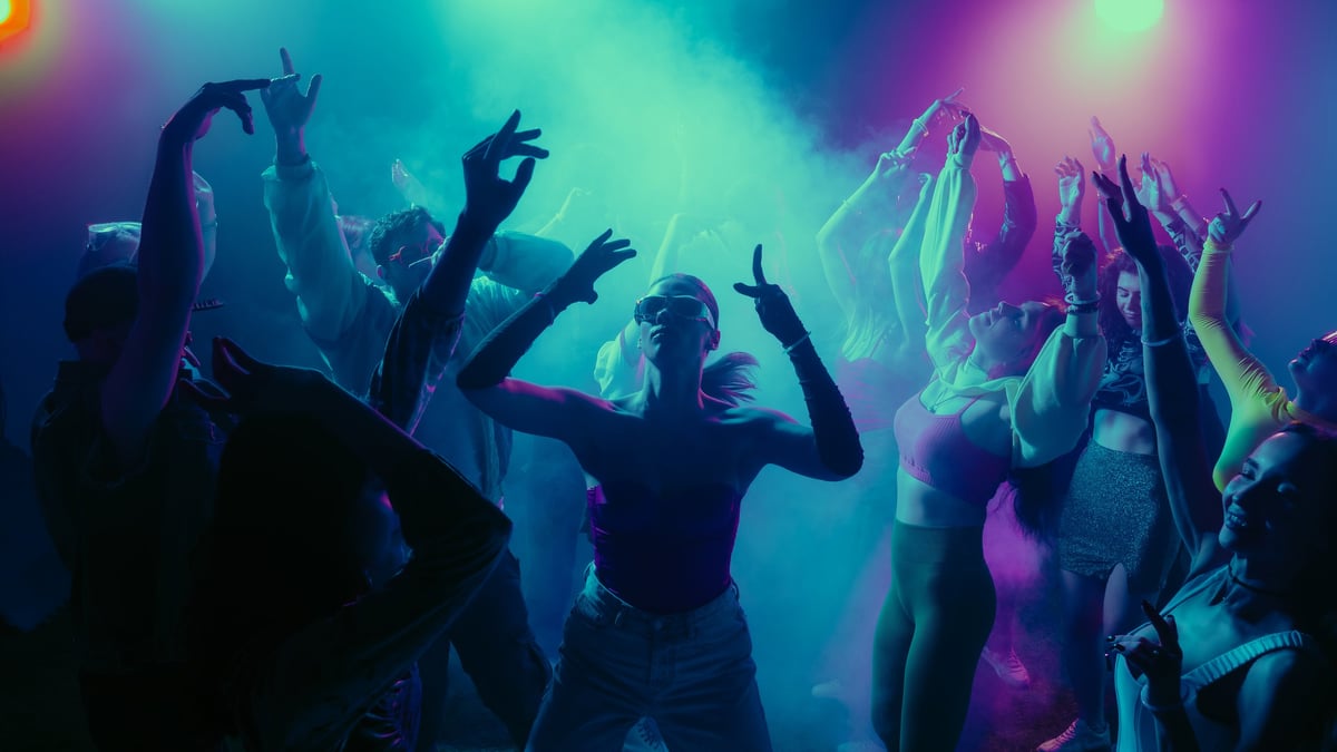 Crowd dancing under colourful lights at a nightlife party